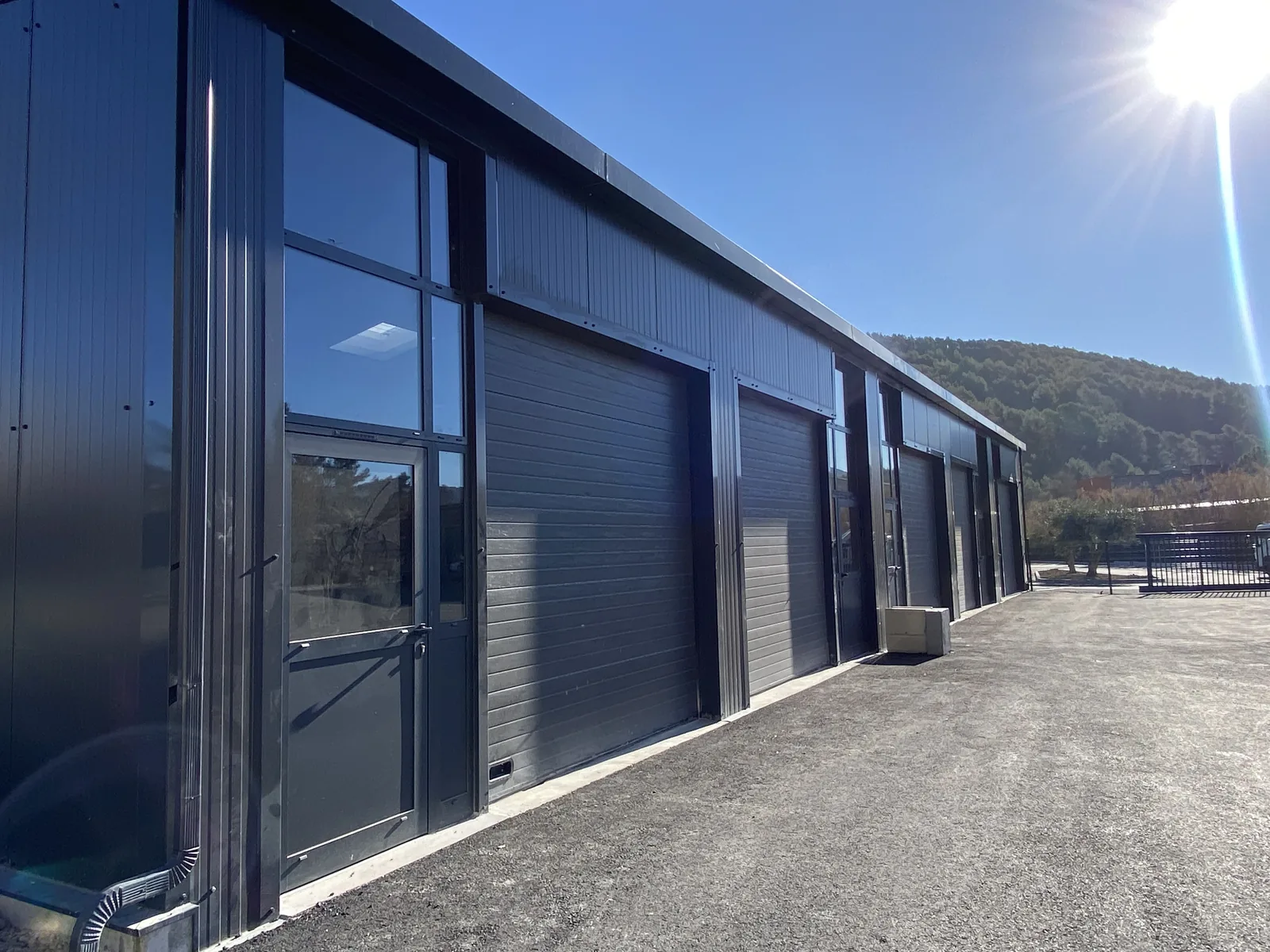 Bâtiment industriel à ossature métallique avec bardage anthracite, portes sectionnelles et menuiseries vitrées