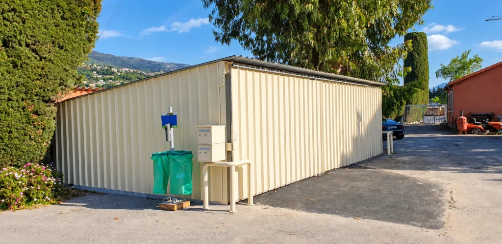 Local de stockage métallique à bardage nervuré ivoire et toiture monopente, adossé en limite de propriété